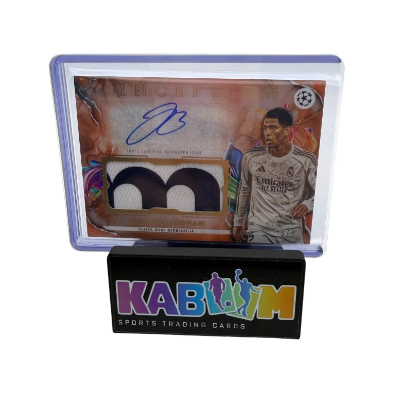 A collectible soccer trading card of Jude Bellingham, featuring an autograph and a dual-color fabric swatch, displayed on a black stand branded 'KABooM SPORTS TRADING CARDS'.